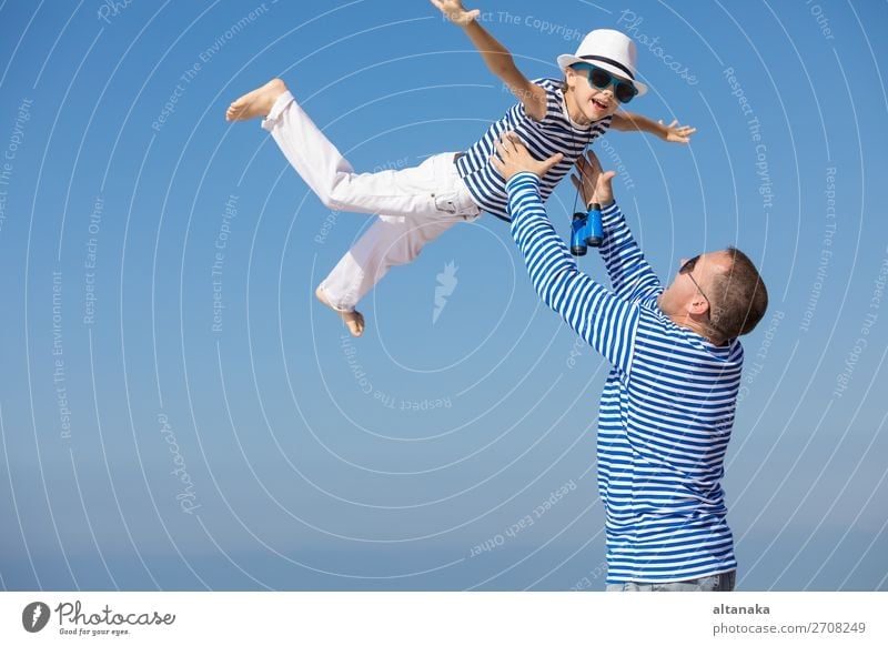 Father and son playing on the beach at the day time. They are dressed in sailor's vests. Concept of sailors on vacation and friendly family. Lifestyle Joy Happy