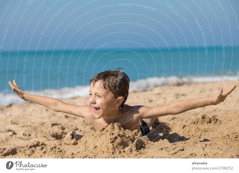 One happy little boy playing on the beach at the day time. Kid having fun outdoors. Concept of vacation. Lifestyle Joy Happy Beautiful Relaxation