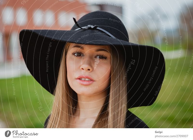 Portrait of an attractive young brunette dark skinned Indian woman in  western black dress holding a cowboy hat in front of her face standing in  white studio background. - a Royalty Free