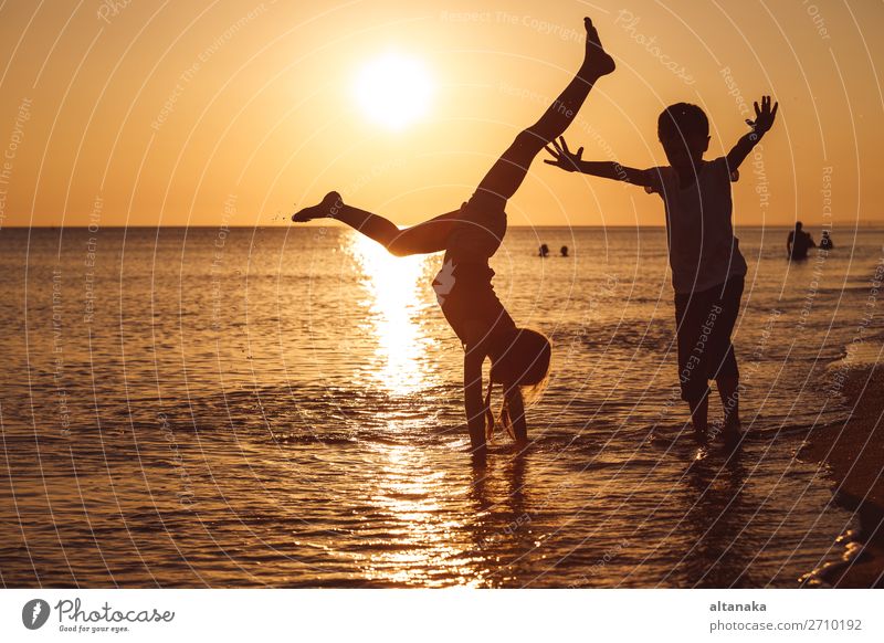 Happy children playing on the beach at the sunset time. Two Kids having fun outdoors. Concept of summer vacation and friendly family. Lifestyle Joy
