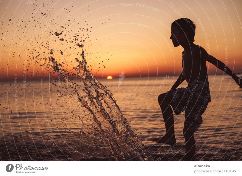 One happy little boy playing on the beach at the sunset time. Kid having fun outdoors. Concept of summer vacation. Lifestyle Joy Happy Beautiful Relaxation