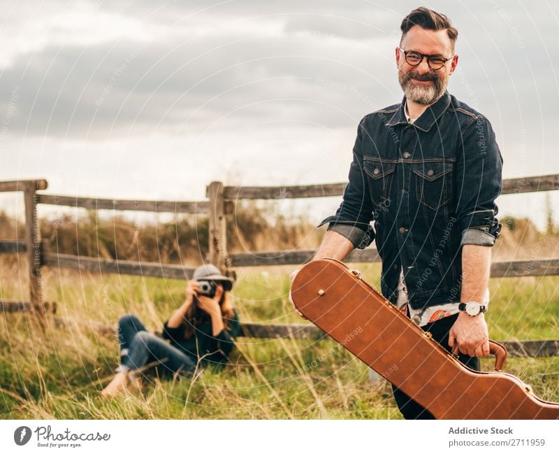 Woman taking shot of man with guitar Man Guitar Nature Musician Photographer To fall Sit Rural Fence Lifestyle Human being Summer Easygoing Acoustic handsome