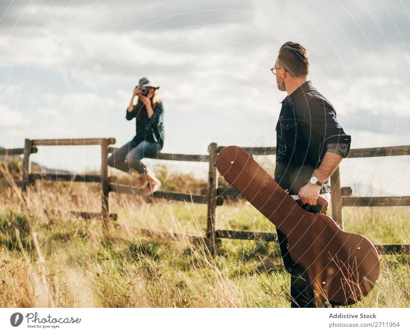 Woman taking shot of man with guitar Man Guitar Nature Musician Photographer To fall Sit Rural Fence Lifestyle Human being Summer Easygoing Acoustic handsome