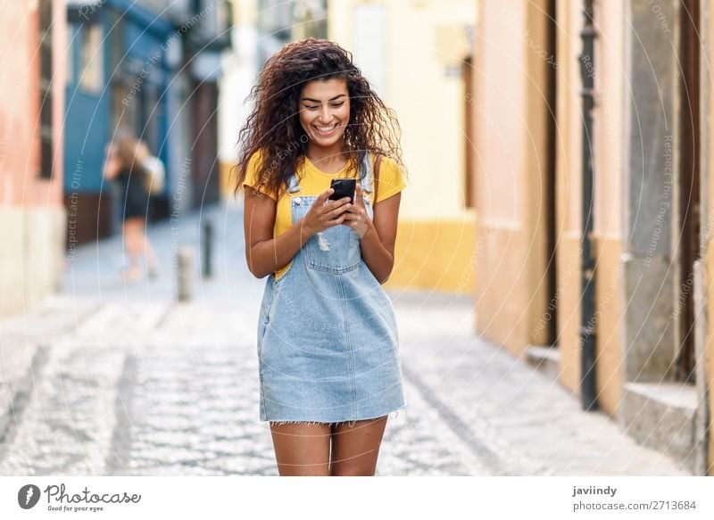 African woman walking on the street looking at her smart phone Lifestyle Style Happy Beautiful Hair and hairstyles Telephone PDA Technology Human being Feminine