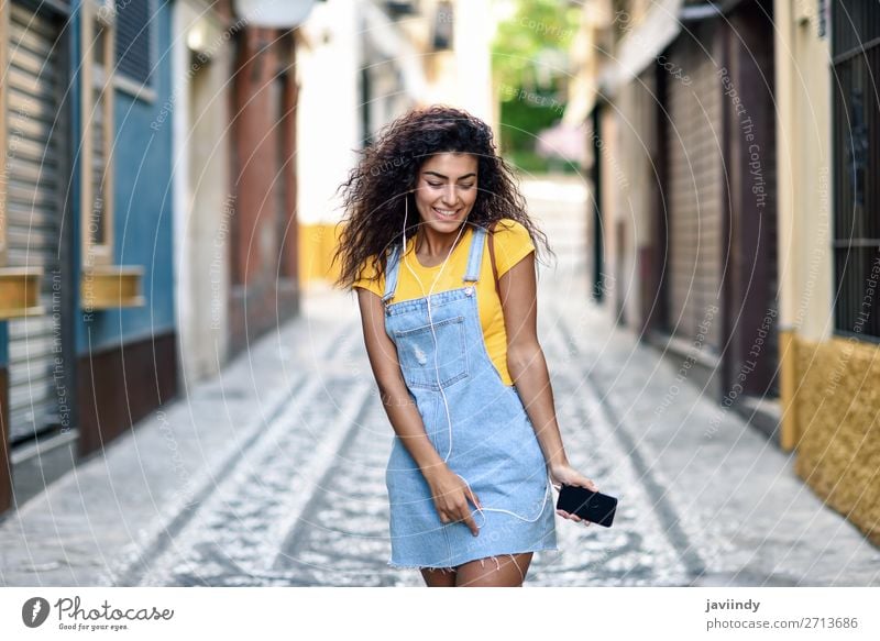 Young Arab woman listening to music with earphones outdoors Lifestyle Style Happy Beautiful Hair and hairstyles Music Telephone PDA Technology Human being