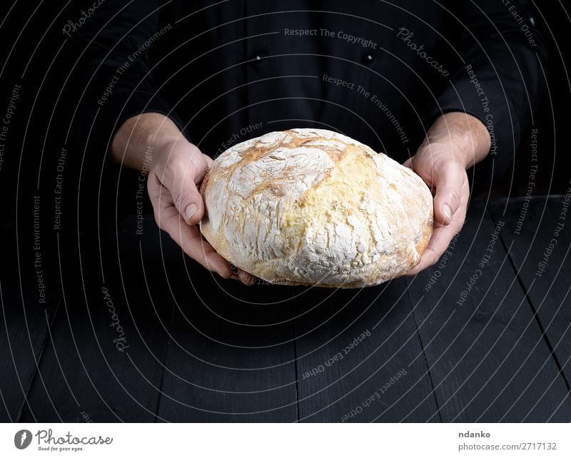 male chef hands hold a whole loaf of baked round bread Bread Nutrition Table Kitchen Cook Human being Man Adults Hand Wood Make Dark Fresh Brown Black White