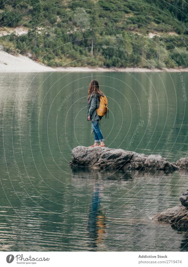 Female backpacker on stone in lake Woman Backpack Lake Mountain Tourism Landscape Action Freedom Tourist Adventure Nature Stone Posture Water Ripple