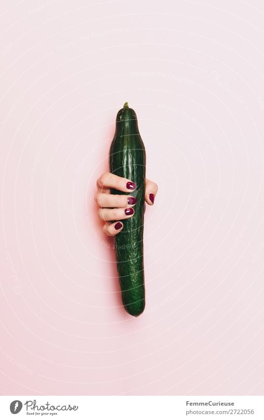 Hand of a woman holding a cucumber Feminine 1 Human being Paper Esthetic Phallic symbol Penis Fertile Cucumber Healthy Eating Vegetable Nail polish Pink Green