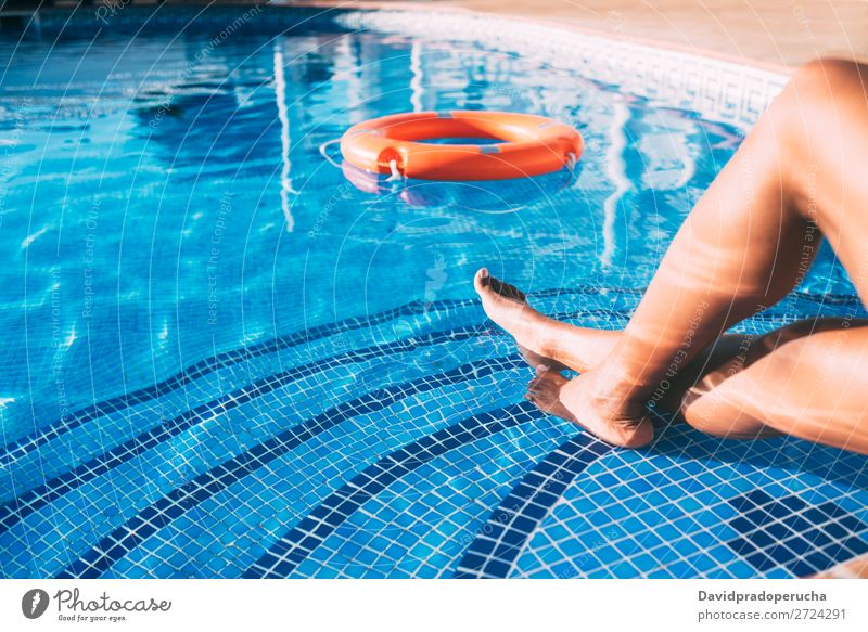 Woman legs in a swimming pool with lifesaver Ethnic Swimming pool Summer Lifeguard Sunbathing Barefoot Legs Pedicure Relaxation Skin tan Water