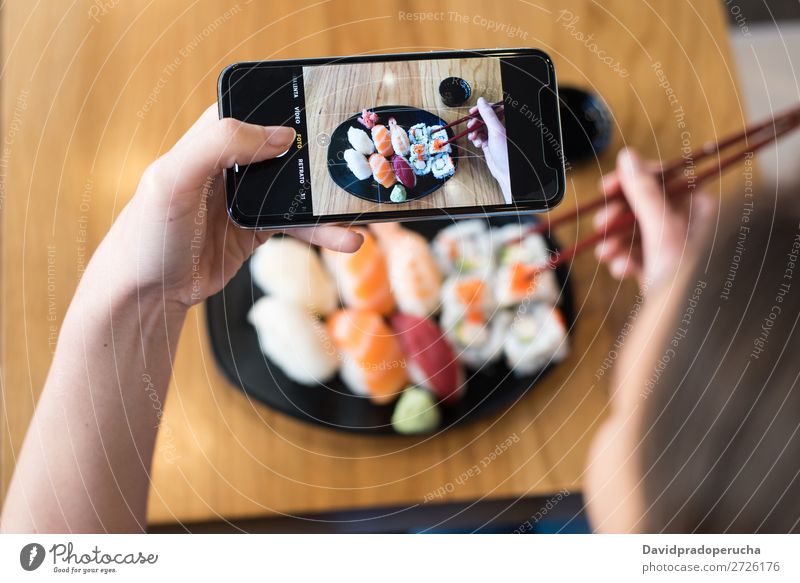 Top view of woman taking photo of sushi on the table Sushi Woman Photography PDA Mobile Telephone Shot Hand Food soy maki california roll Chopstick Roll Crops