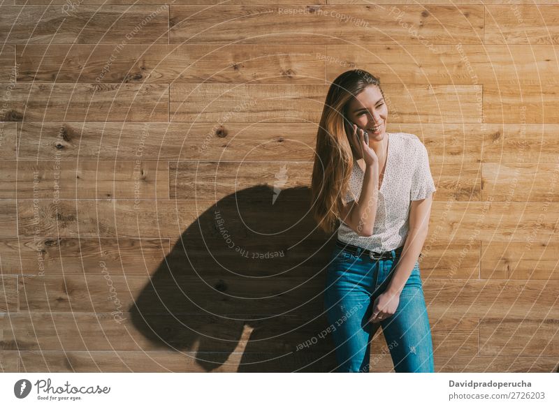 Happy woman using smartphone at a wooden wall Woman PDA Telephone Mobile Communication device Smiling Looking away Portrait photograph Wood Background picture