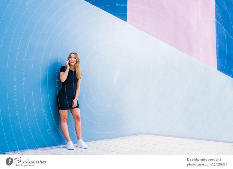 Happy young woman on the mobile phone by a colorful wall Woman Multicoloured Blonde Telephone Wall (building) Mobile Technology Dress Exterior shot