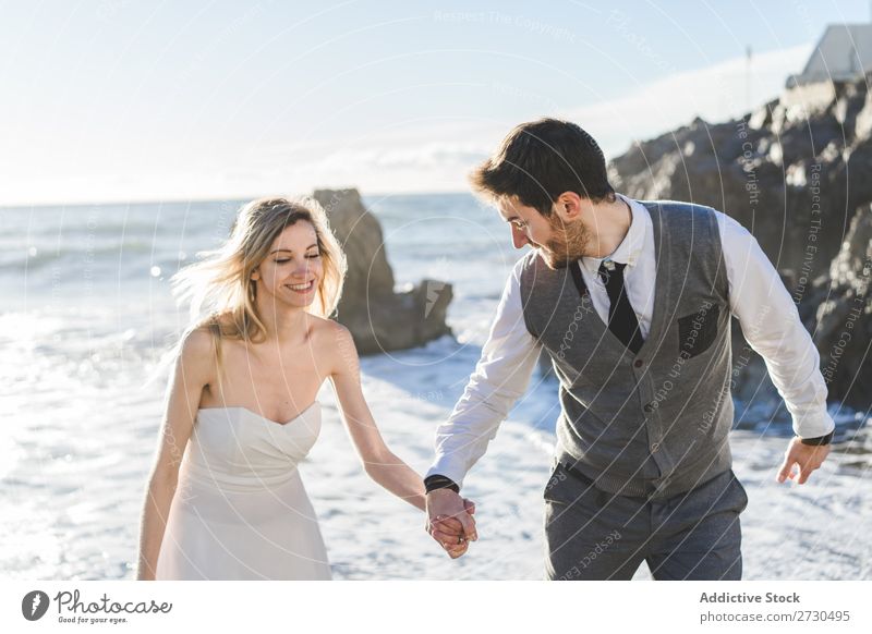 Beautiful bridal couple walking on shore Couple Beach Happiness seaside holding hands Cheerful Exterior shot Together Contentment Summer Dress Wedding