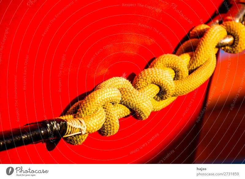 Mooring line to a red fishing cutter Design Navigation Maritime mooring rope Knot Yellow Red boat ship's side variegated colourful sunny light lashed Harbour