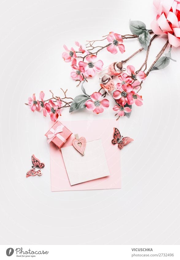 Lovely greeting card mock up with flowers, ribbon, little gift box and hearts in coral color on white background, top view. Flat lay. Abstract love and holidays concept. Blog layout