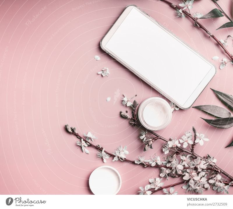Smartphone mock up on pastel pink desktop  with cosmetic and flowers, top view. Beauty blog and female business concept smartphone background blossom branches