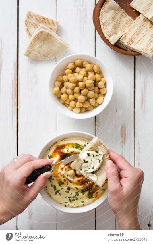 woman dipping hummus with pita bread on white wooden table Hummus Bread Food Healthy Eating Food photograph Nutrition Chickpeas Coriander Lemon Olive oil Cream