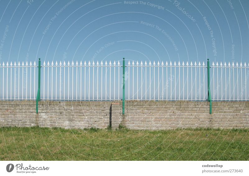 ornamentally ironic Wall (barrier) Wall (building) Line Arrow Blue Green Protection Fence Fence post Sky Grass Border Brick wall Cloudless sky Colour photo