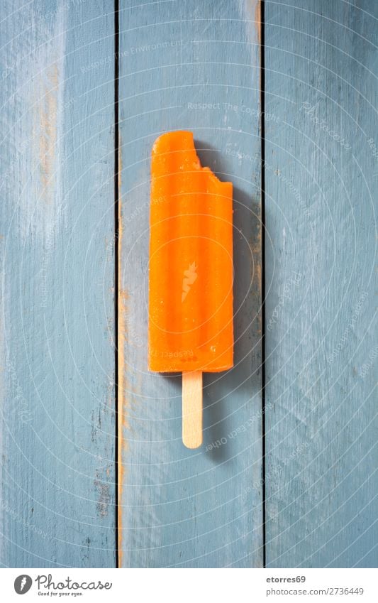 Orange popsicle on blue wooden table. Top view Baked goods Summer Ice Ice cream Cold Food Healthy Eating Food photograph Dessert Frozen Icing Vegan diet stick