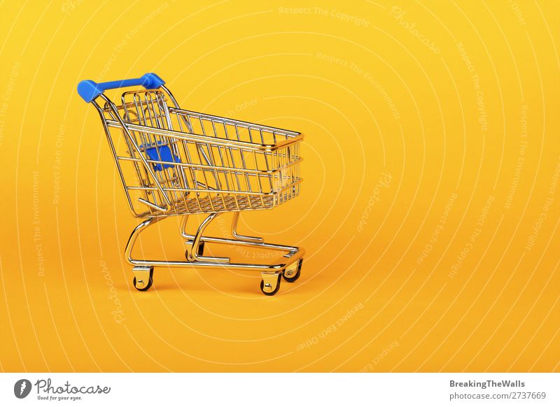 Close up retail shopping cart over yellow Shopping Economy Industry Trade Business SME Paper Toys Metal Plastic Yellow Colour Retail sector Supermarket Side