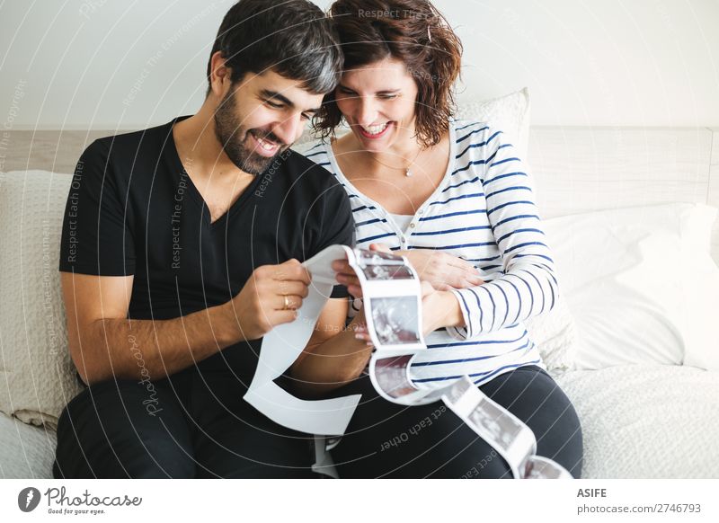 Happy pregnant couple looking at the ultrasound images Beautiful Life Baby Woman Adults Man Parents Mother Father Family & Relations Couple Smiling Love Sit