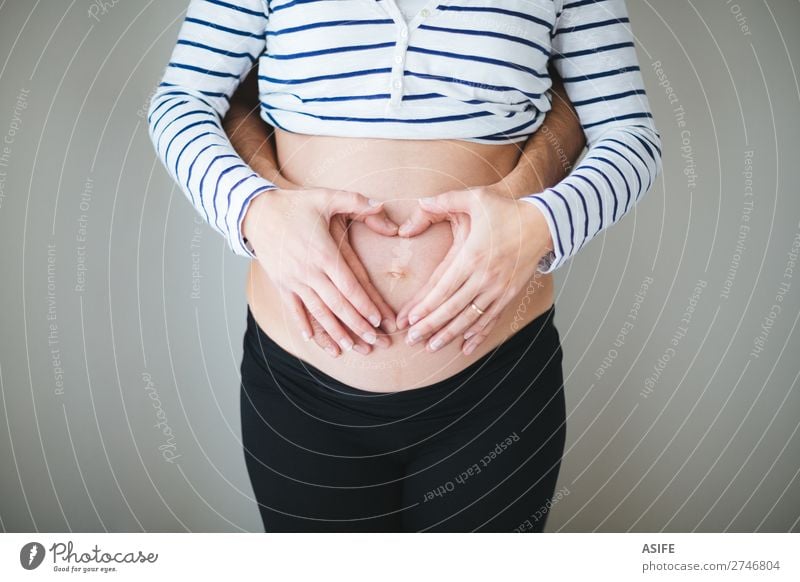 Heart wirh couple hands on the pregnant belly - a Royalty Free