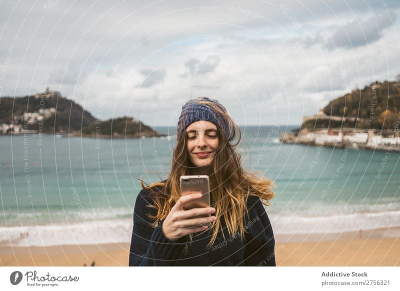 Woman with smartphone at the seaside Youth (Young adults) Coast Ocean pretty PDA using browsing Surfing Attractive Hat Nature Water Vacation & Travel Beach