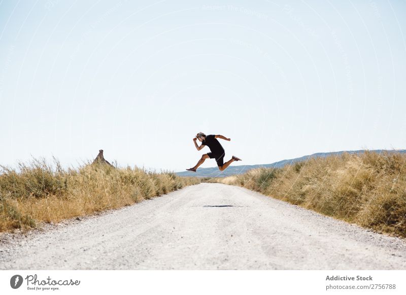 Man jumping on road prairie Street Vacation & Travel Lifestyle Human being Adults Nature Adventure Trip Tourist Landscape Grass Vantage point Sky Clear