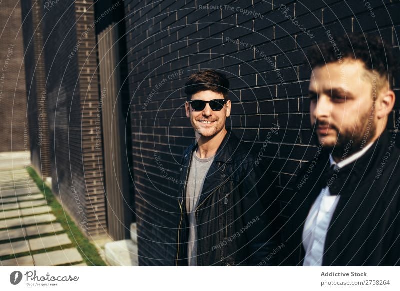 A lovely gay couple holding hands on the background of brick wall. standing looking at camera posing homosexual pair male two together lifestyle relationship