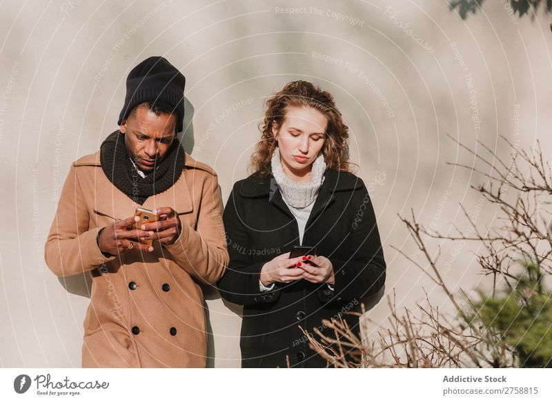 Couple in warm clothes with smartphones multiethnic Style Street PDA using Stand Easygoing Beautiful Mixed race ethnicity Black Youth (Young adults) Together