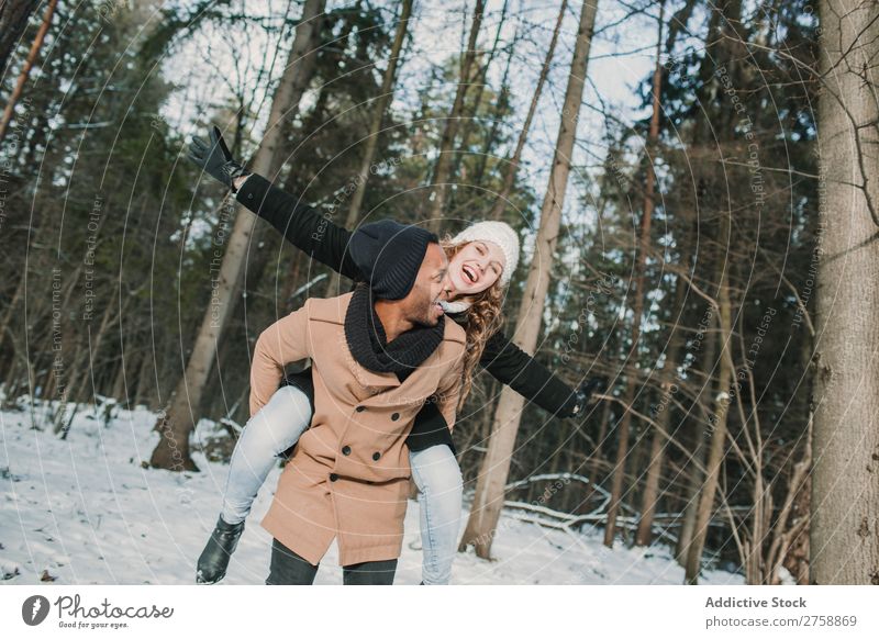 Couple having fun in winter forest multiethnic Style warm clothes Easygoing Nature Forest Winter Snow piggyback Beautiful Mixed race ethnicity Black