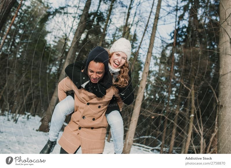 Couple having fun in winter forest multiethnic Style warm clothes Easygoing Nature Forest Winter Snow piggyback Beautiful Mixed race ethnicity Black