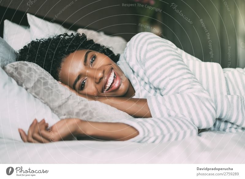 close up of a pretty black woman with curly hair smiling and lying on bed looking at the camera Woman Bed Portrait photograph Close-up Lie (Untruth) Black