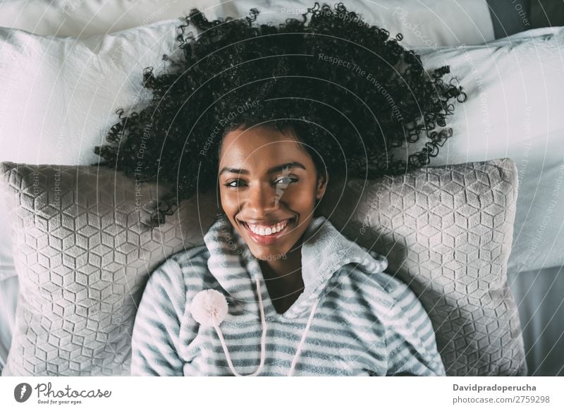 Beautiful black woman with curly hair smiling and lying on bed looking at the camera Woman Bed Black Smiling African pretty Bird's-eye view Close-up Curly hair