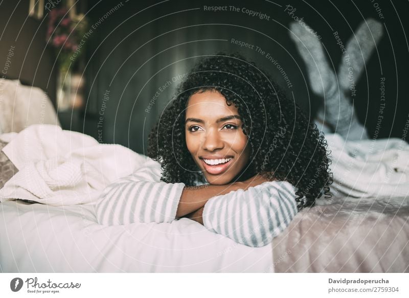 close up of a pretty black woman with curly hair smiling and lying on bed looking away Woman Bed Portrait photograph Close-up Lie (Untruth) Black Smiling