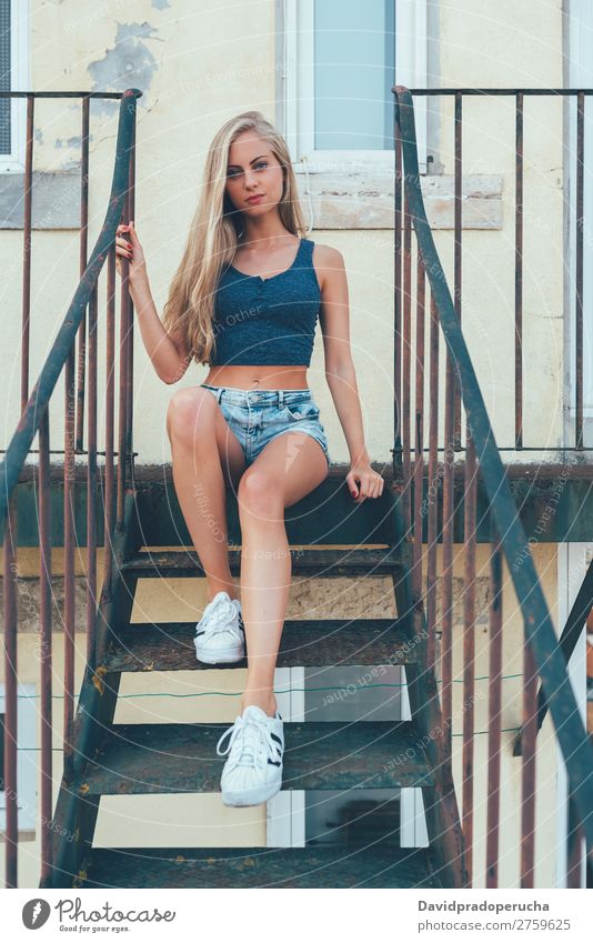 Young fit beautiful blonde woman sitting on the stairs posing Woman Portrait photograph Smiling Youth (Young adults) Considerate pretty Athletic Stairs Sit Blue