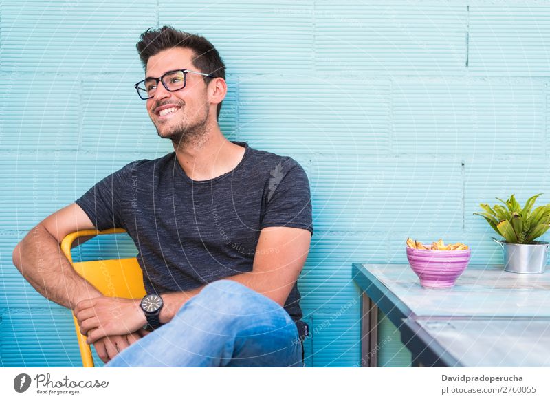 Happy young man seating in a restaurant Adults Loneliness Attractive Beautiful Blue Bright Caucasian Coffee Café Multicoloured enjoying Food Fries Guy handsome