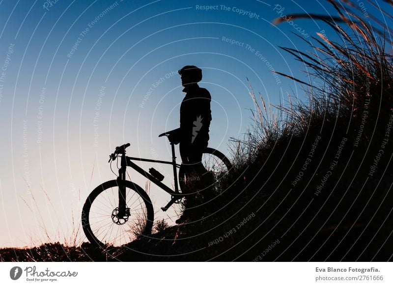 silhouette of a Cyclist with Bike at Sunset. Sports Lifestyle Relaxation Leisure and hobbies Adventure Summer Mountain Cycling Bicycle Masculine Young man