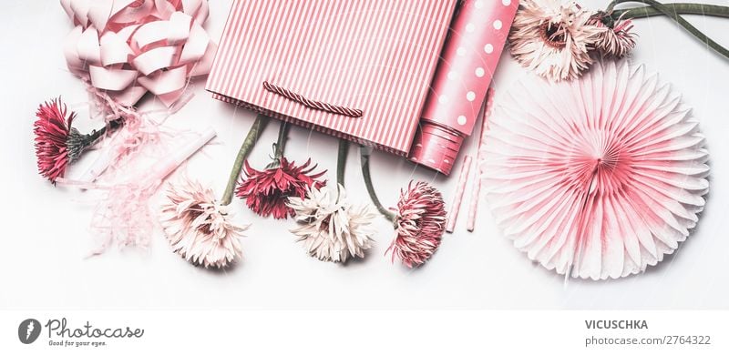 Composition of pink accessories to female holidays: Mothers day , Womens day, birthday or wedding. Paper shopping bag with flowers,paper, party fan and ribbon on white background, top view