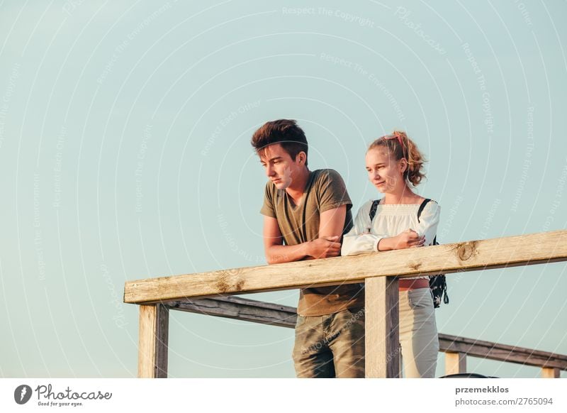 Smiling young woman and man sitting on a pier over the sea Lifestyle Joy Happy Leisure and hobbies Vacation & Travel Summer Ocean Human being Boy (child) Couple