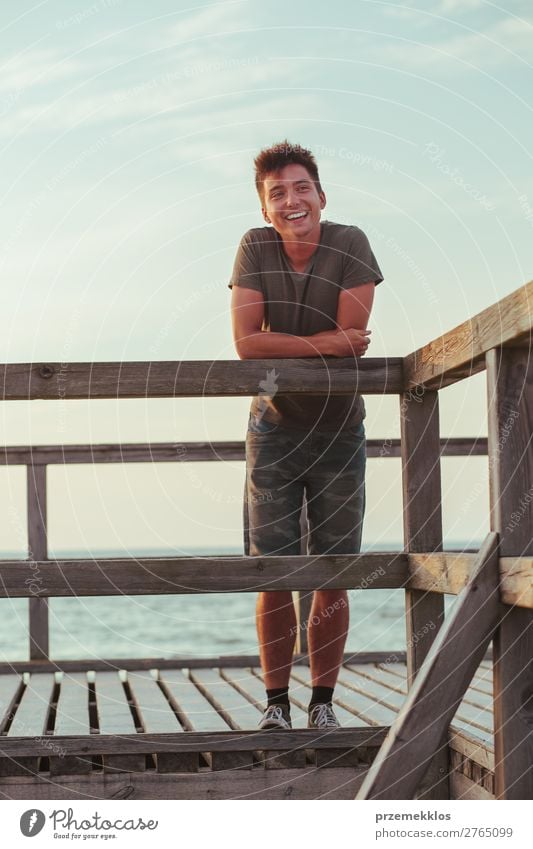 Smiling happy young man standing on a pier over the sea Lifestyle Joy Happy Leisure and hobbies Vacation & Travel Summer Ocean Human being Boy (child)