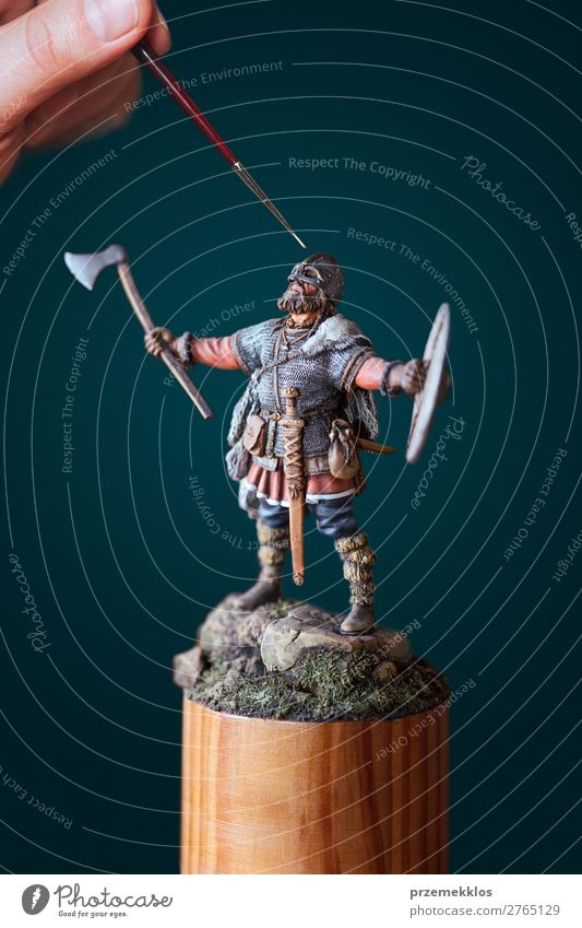 Man painting a little figure of Viking Leisure and hobbies Hand Small close Conceptual design Figure Miniature Model paintbrush perfection Colour photo Detail