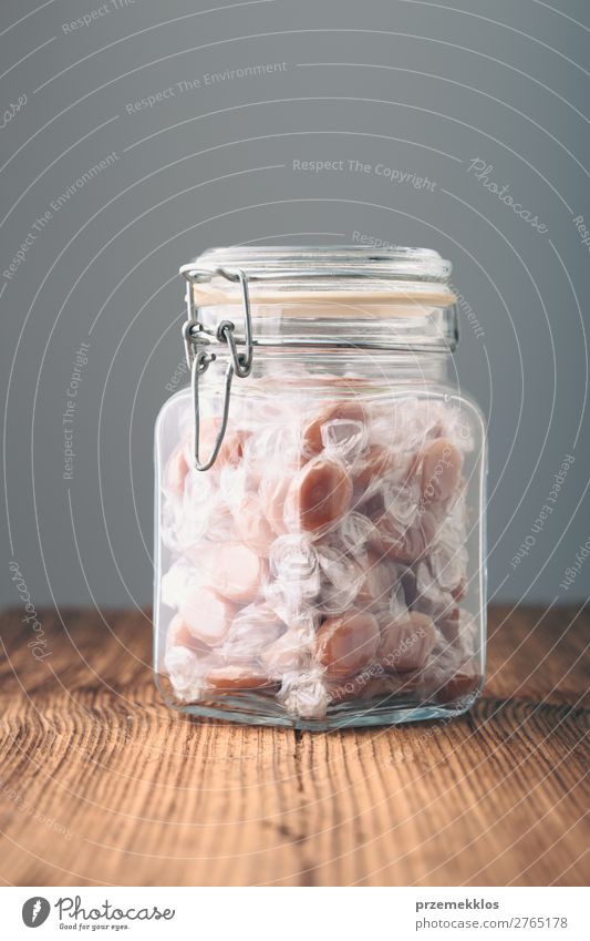 Jar filled with caramel milky candies on table Dessert Candy Nutrition Eating Diet Table Wood Delicious addiction Caramel eat food jar Quit Objective Sacrifice