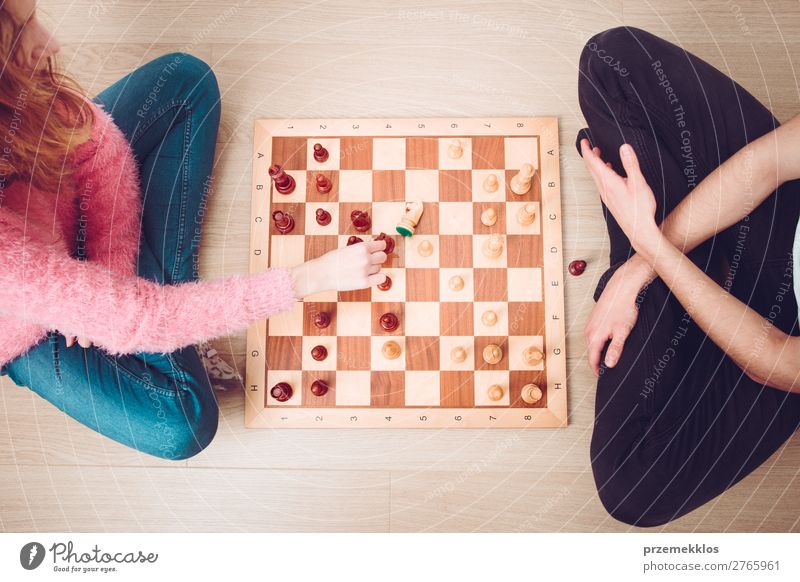 Girl and boy playing chess at home. Lifestyle Leisure and hobbies Playing Chess Success Human being Boy (child) Woman Adults Man To enjoy Smart Black White