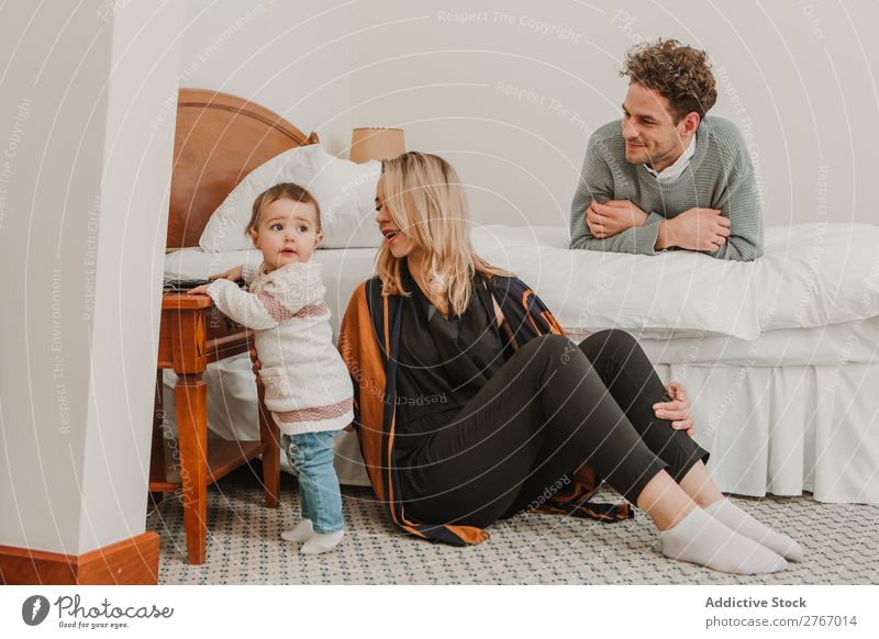 Cheerful couple with child on be Family & Relations Mother Father Child Playing Human being Hotel Room Bedroom Home Interior design Furniture Flat (apartment)