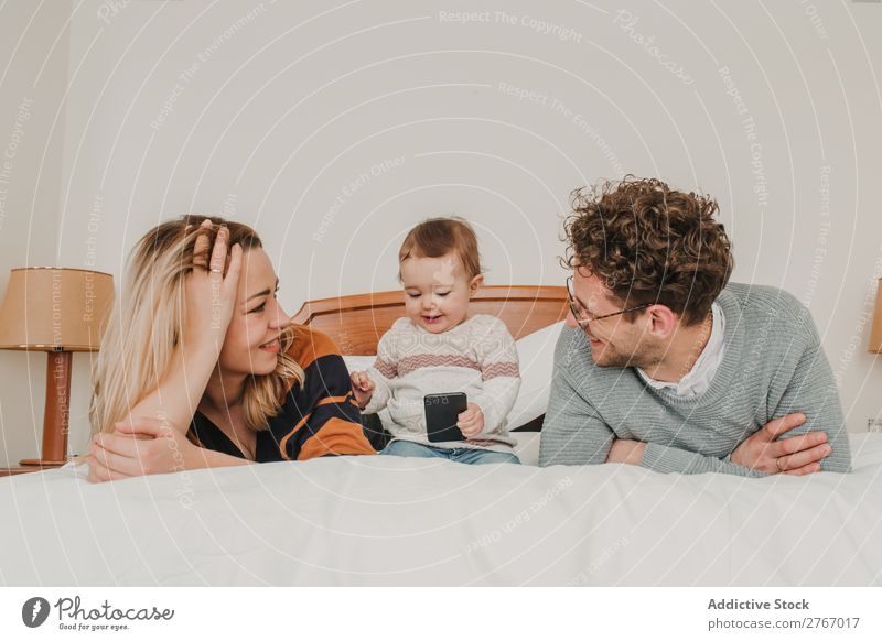 Cheerful couple with child on bed Family & Relations Mother Father Child PDA Playing Human being Hotel Room Bedroom Home Interior design Furniture