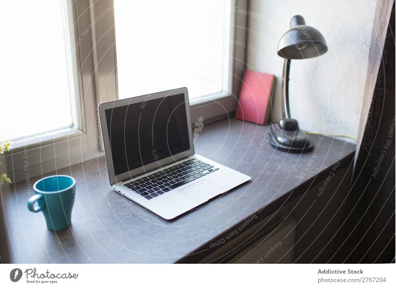Laptop at window Notebook Cup Lamp Window Workplace Office Coffee Computer Desk Home House (Residential Structure) Business Screen desktop Table workspace