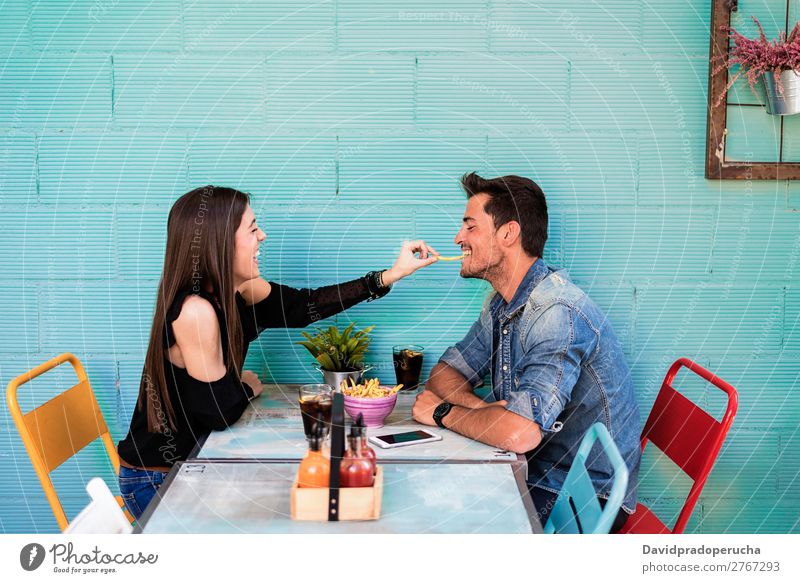 Happy young couple seating in a restaurant Adults Attractive Beautiful Caucasian Coffee Cola Couple Eating enjoying Woman Food Friendship Fries having