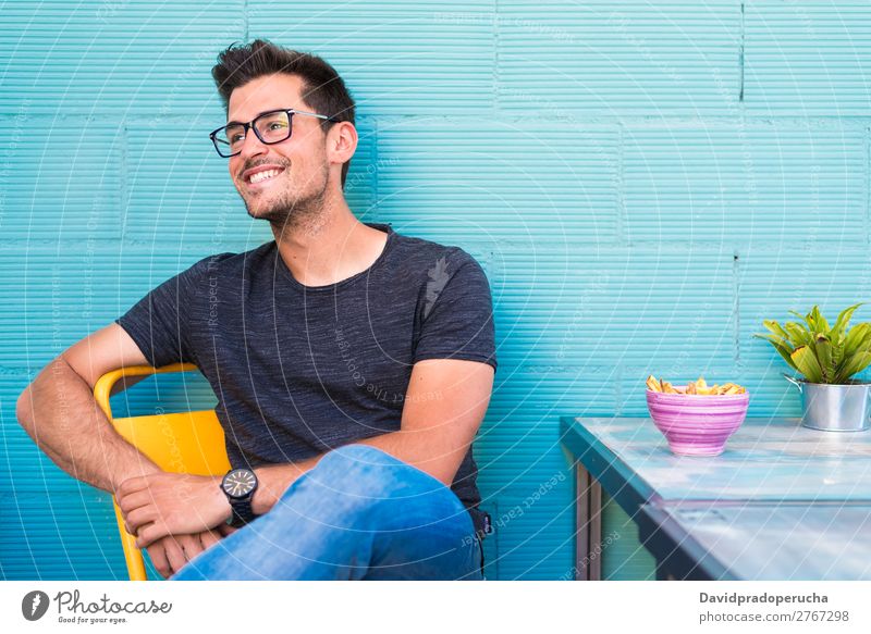 Happy young man seating in a restaurant Adults Loneliness Attractive Beautiful Blue Bright Caucasian Coffee Café Multicoloured enjoying Food Fries Guy handsome
