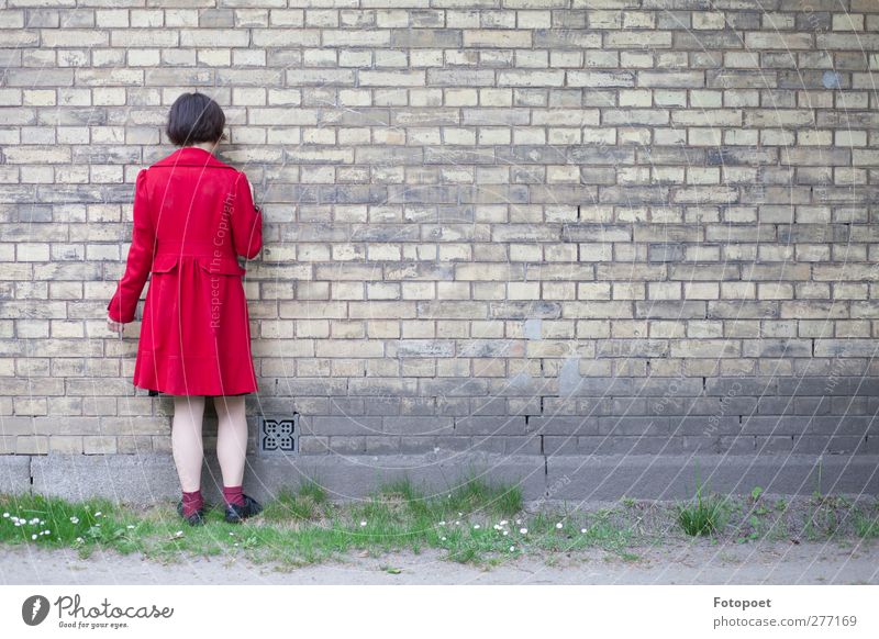 against the wall Feminine Young woman Youth (Young adults) 1 Human being 18 - 30 years Adults Wall (barrier) Wall (building) Coat Black-haired Touch Stand Red